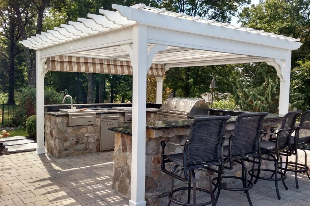An outdoor kitchen with a pergola and bar stools.